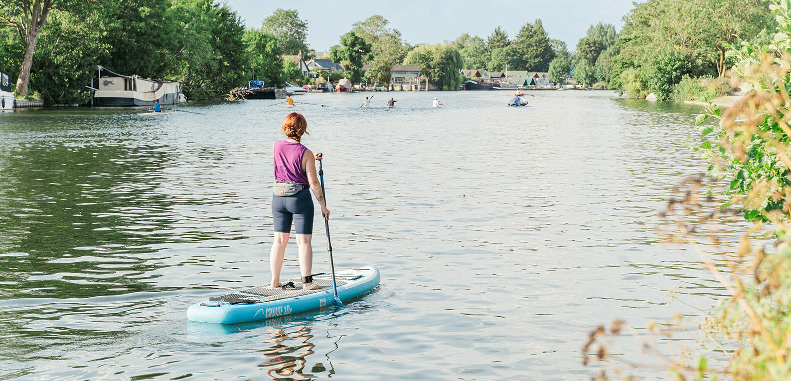 http://A%20woman%20paddleboarding%20on%20a%20peaceful%20river%20surrounded%20by%20greenery